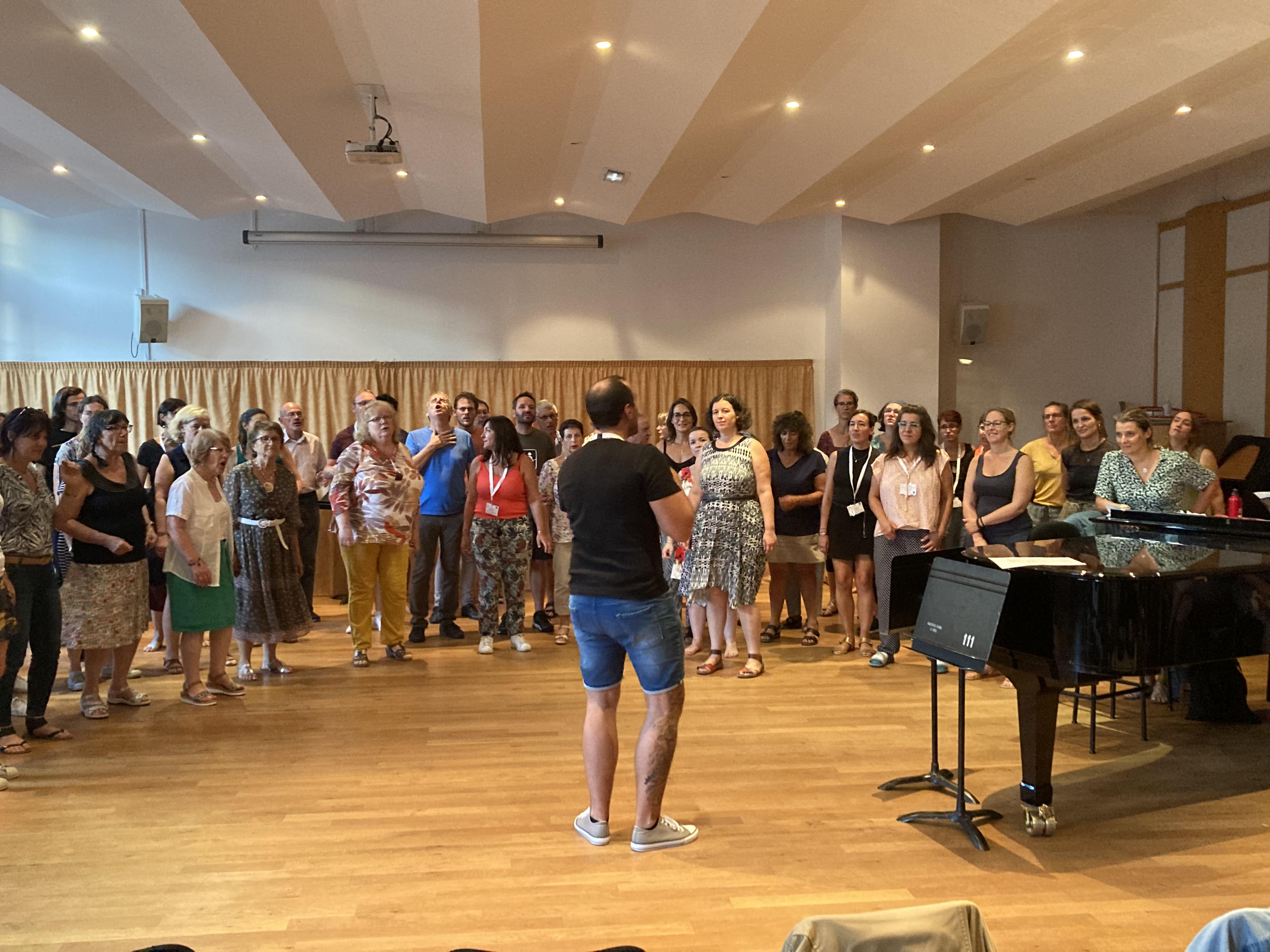 Un groupe en formation autour d’un chef de chœur et d’un piano